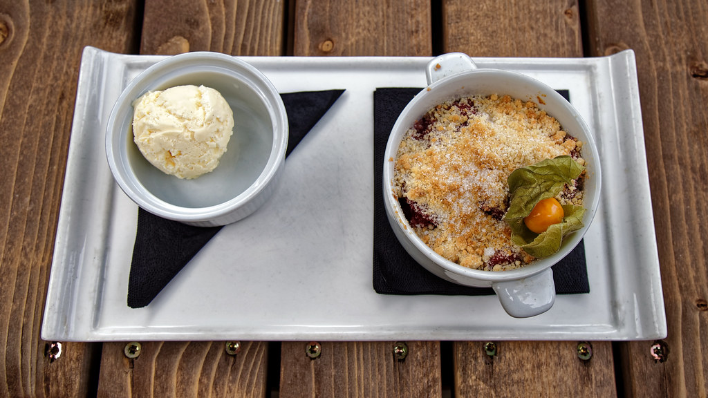 An individual fruit crumble in a small dish, served with a scoop of ice cream
