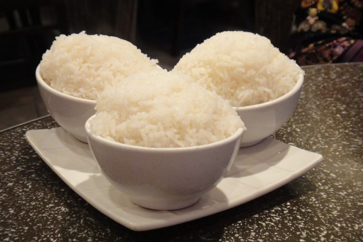Three white bowls filled with steamed white rice