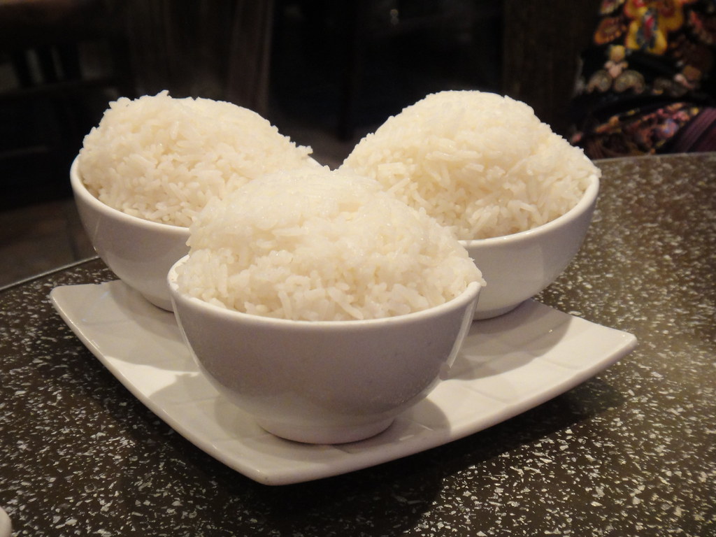 Three white bowls filled with steamed white rice