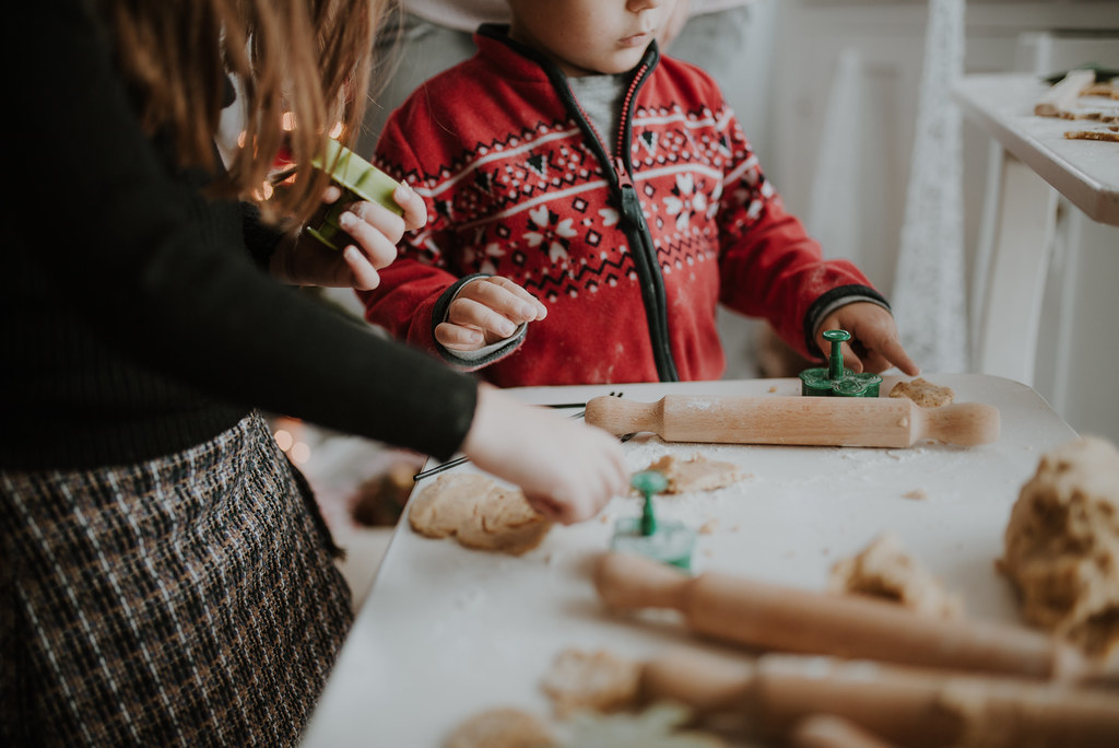 Two children cutting shapes from cookie dough at a child-height table