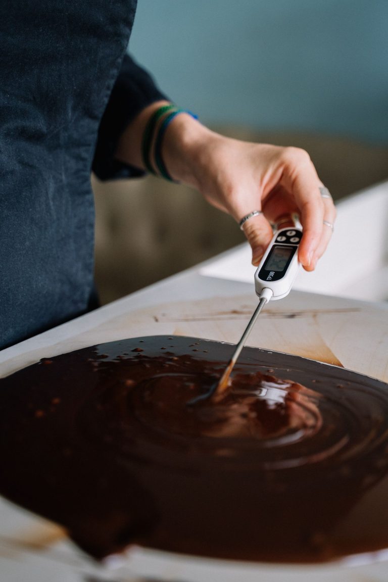 A digital probe thermometer being used to check the temperature of melted chocolate