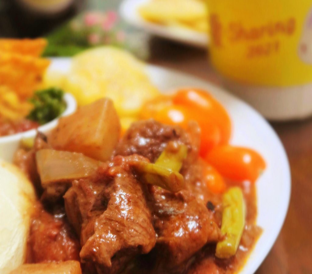 A plate of beef stew with chunks of potato and vegetables in a rich sauce