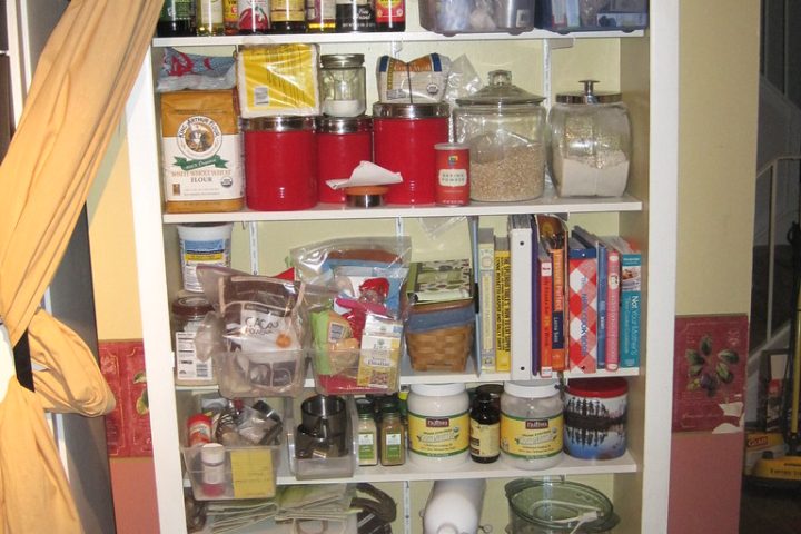 A pantry cupboard with shelves of jars, packets and cookbooks