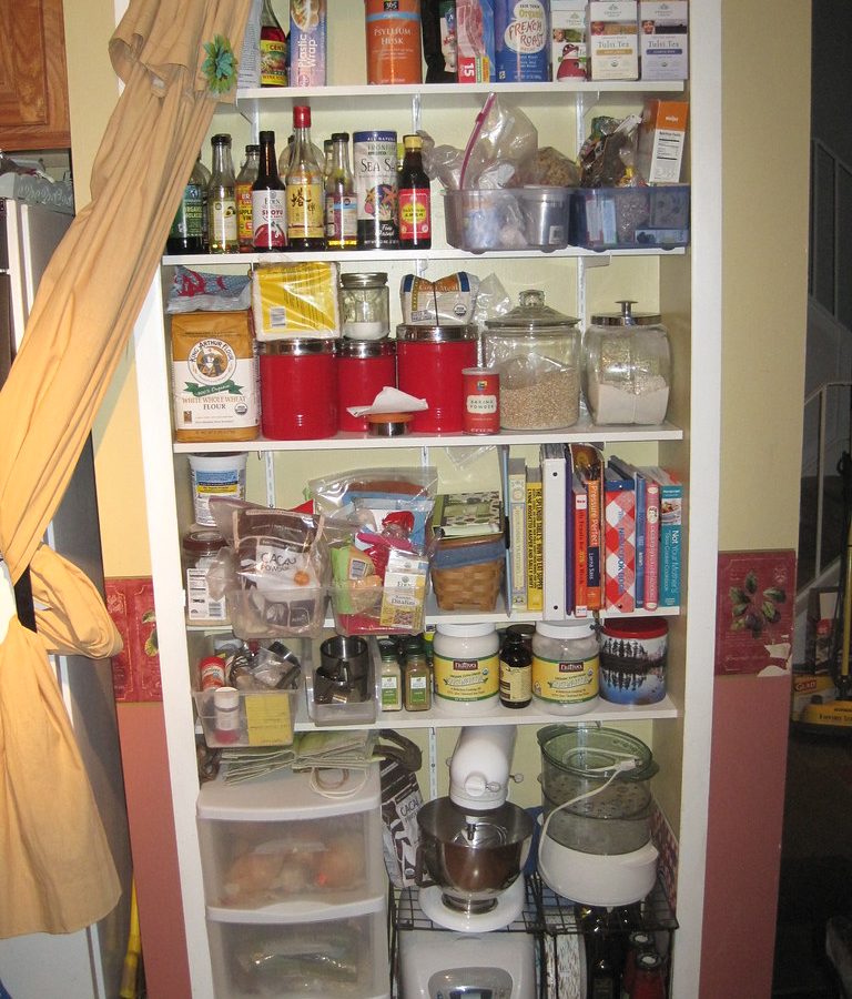 A pantry cupboard with shelves of jars, packets and cookbooks