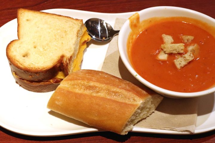 A grilled cheese sandwich cut in half, served with a bowl of tomato soup