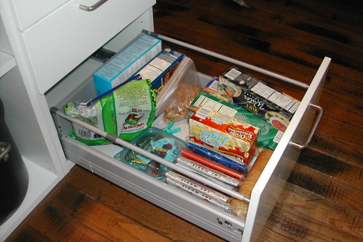 An open kitchen drawer filled with snack boxes and packets