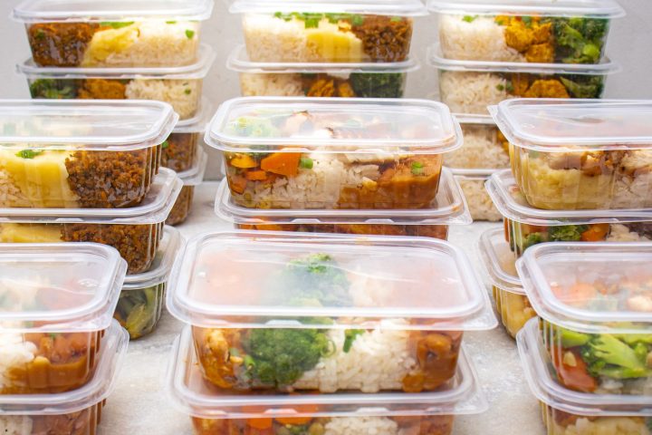 Rows of stacked meal prep containers filled with rice and vegetables