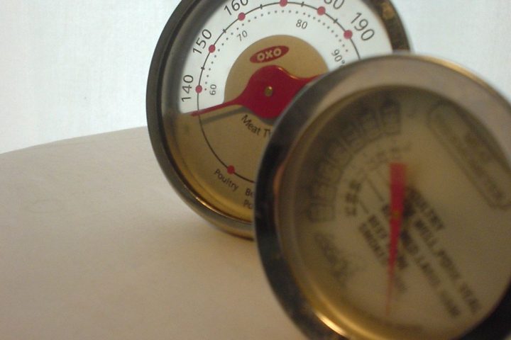 Two dial meat thermometers standing on a kitchen worktop