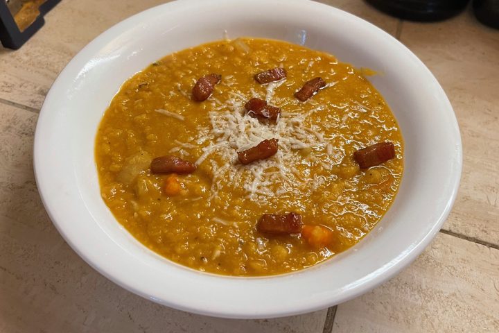 A white bowl of thick orange-yellow red lentil soup