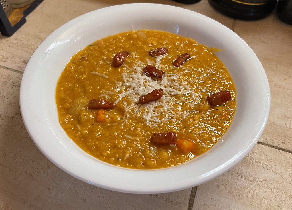 A white bowl of thick orange-yellow red lentil soup
