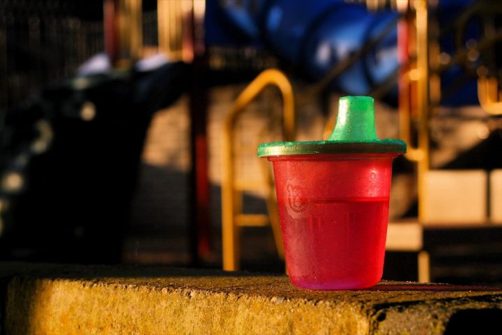 A small red sippy cup with a green spout