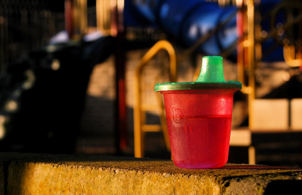 A small red sippy cup with a green spout
