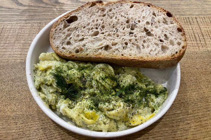 Scrambled eggs scattered with herbs, served with a thick slice of sourdough toast