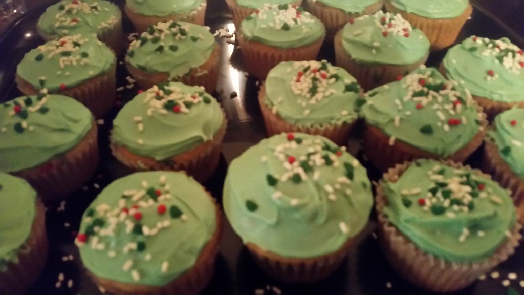A tray of cupcakes topped with pale green buttercream and sprinkles