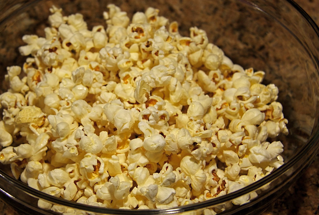 A glass bowl full of freshly popped popcorn